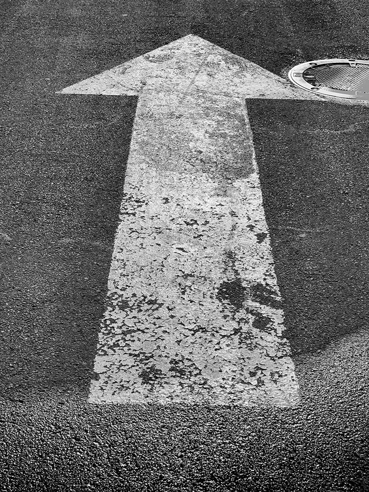 B&W Photo of Arrow on Asphalt Pavement.